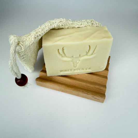 Bar of soap with a deer emblem on a wooden stand with a rope and wooden cinch.