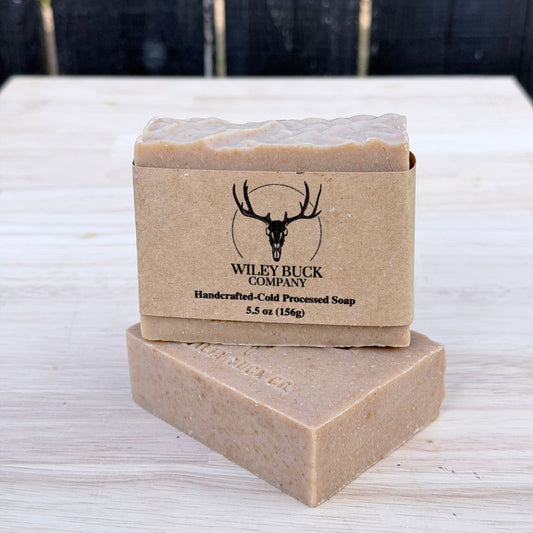 Two bars of soap with a brown box labeled 'Wiley Buck Company' on a light wooden surface.