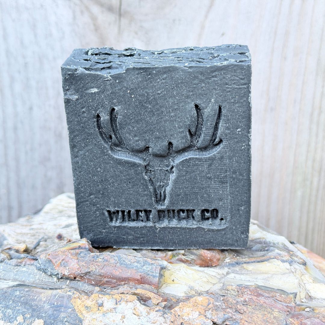 Bar of soap with a deer skull design and 'Wiley Buck Co' branding on a stone surface.