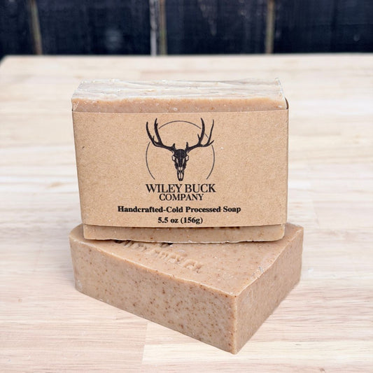Two bars of Wiley Buck Company soap on a wooden surface with a dark background.