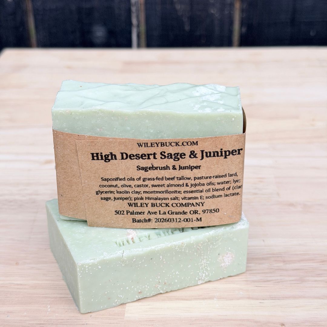 Two bars of soap with a brown label on a wooden surface