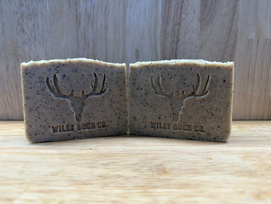 Two Cowboy Coffee soap bars with a deer head design and 'Wiley Buck Co.' branding on a wooden surface.