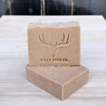 Two bars of Wiley Buck Co. soap stacked on a wooden surface