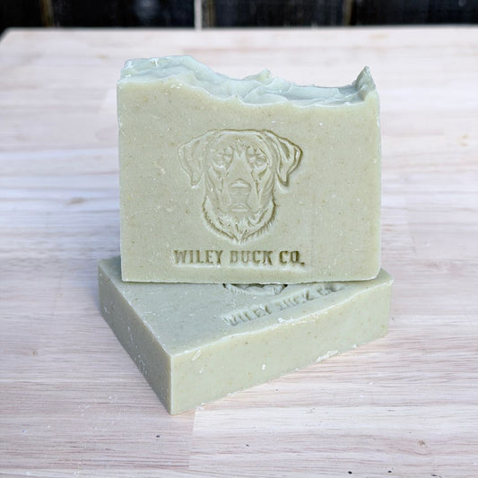 Two green bars of soap with a dog logo and 'Wiley Buck Co.' text on a wooden surface.