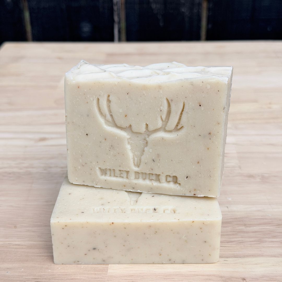 Two bars of soap stacked on a wooden surface with 'Wiley Buck Co.' branding.