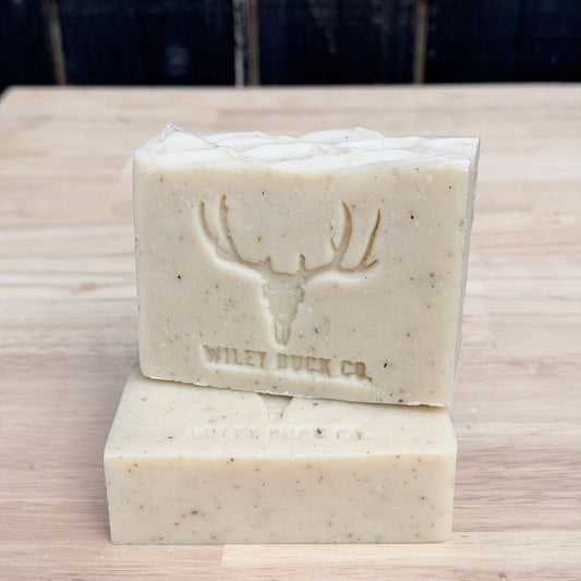 Two bars of soap stacked on a wooden surface with 'Wiley Buck Co.' branding.