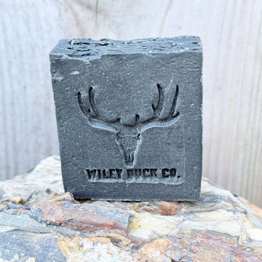 Bar of soap with a deer skull design and 'Wiley Buck Co' branding on a stone surface.