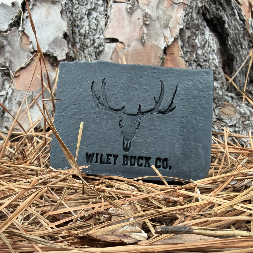 Blackout Soap bar by Wiley Buck Co. – deep black charcoal and tallow soap resting on pine needles in the forest