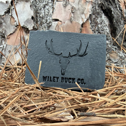 Blackout Soap bar by Wiley Buck Co. – deep black charcoal and tallow soap resting on pine needles in the forest